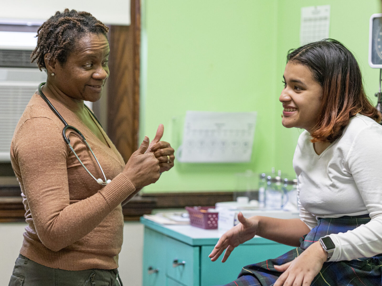An Education Plus Health nurse practitioner giving thumbs up to a student in a white shirt