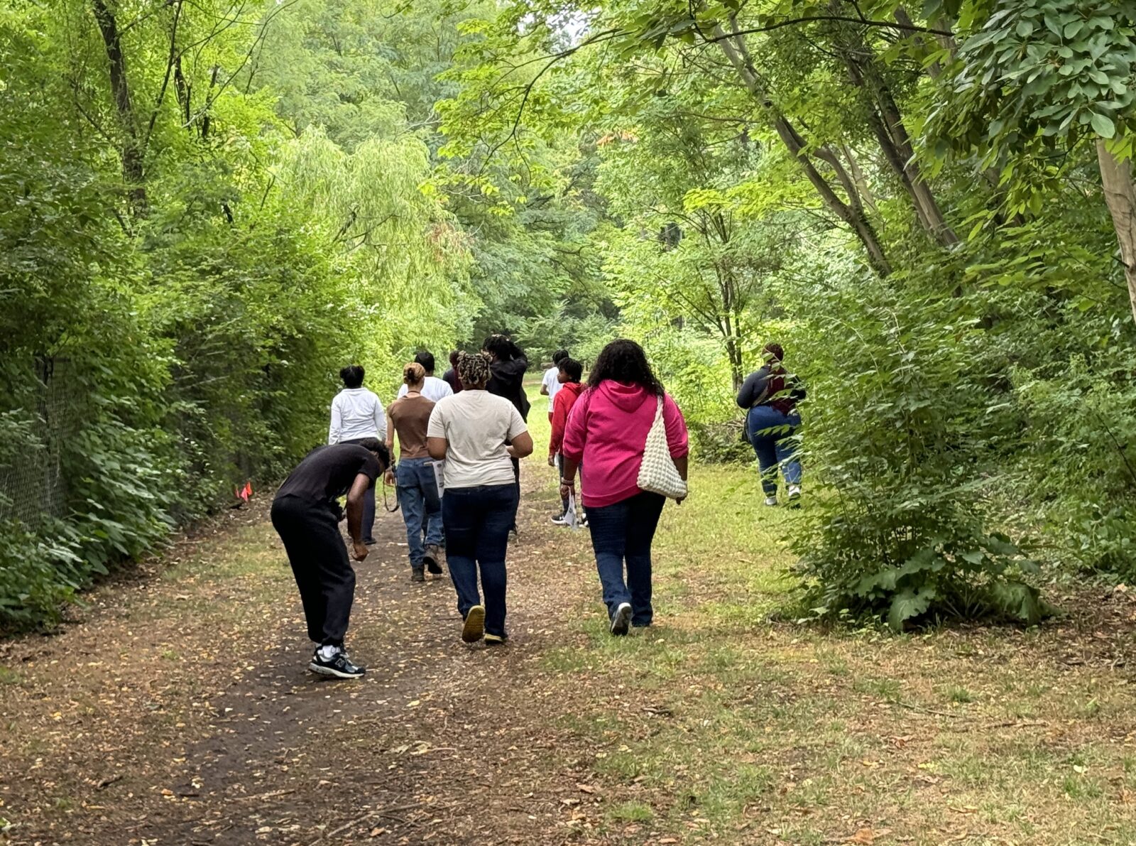Members of the West Philadelphia Youth Environmental Justice Council with their backs turned to the camera walking the trails at The Discovery Center.